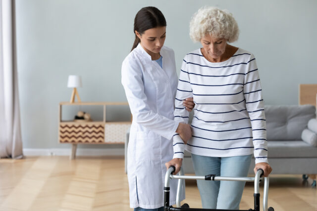 Young doctor helping an older woman use a walker