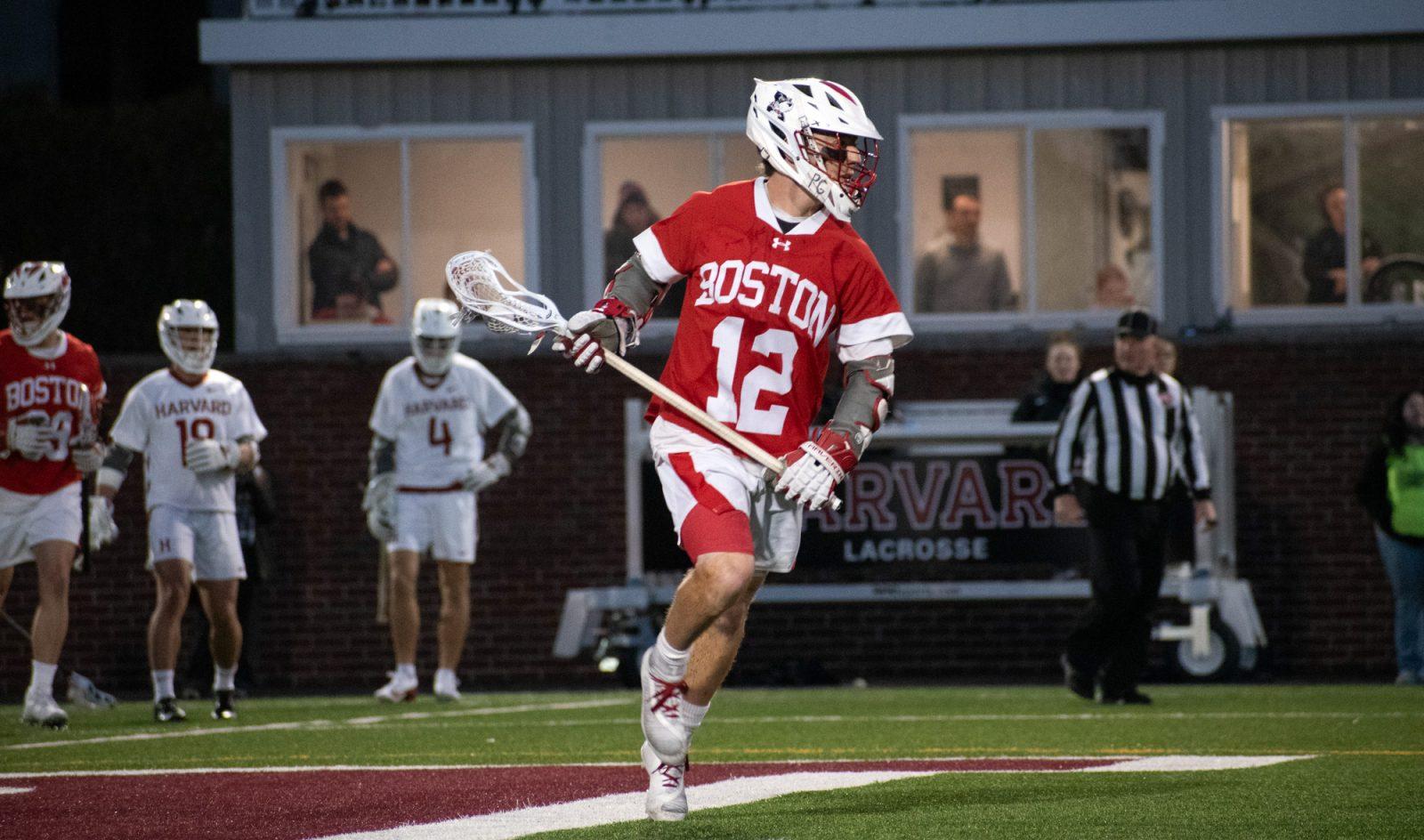 Senior attack Zach Travaglini (12) cradles the ball against Harvard University March 25. Boston University’s men lacrosse team won in a 16-4 victory against Holy Cross Saturday evening at Nickerson Field. JOHN DOWNES/DFP PHOTOGRAPHER 
