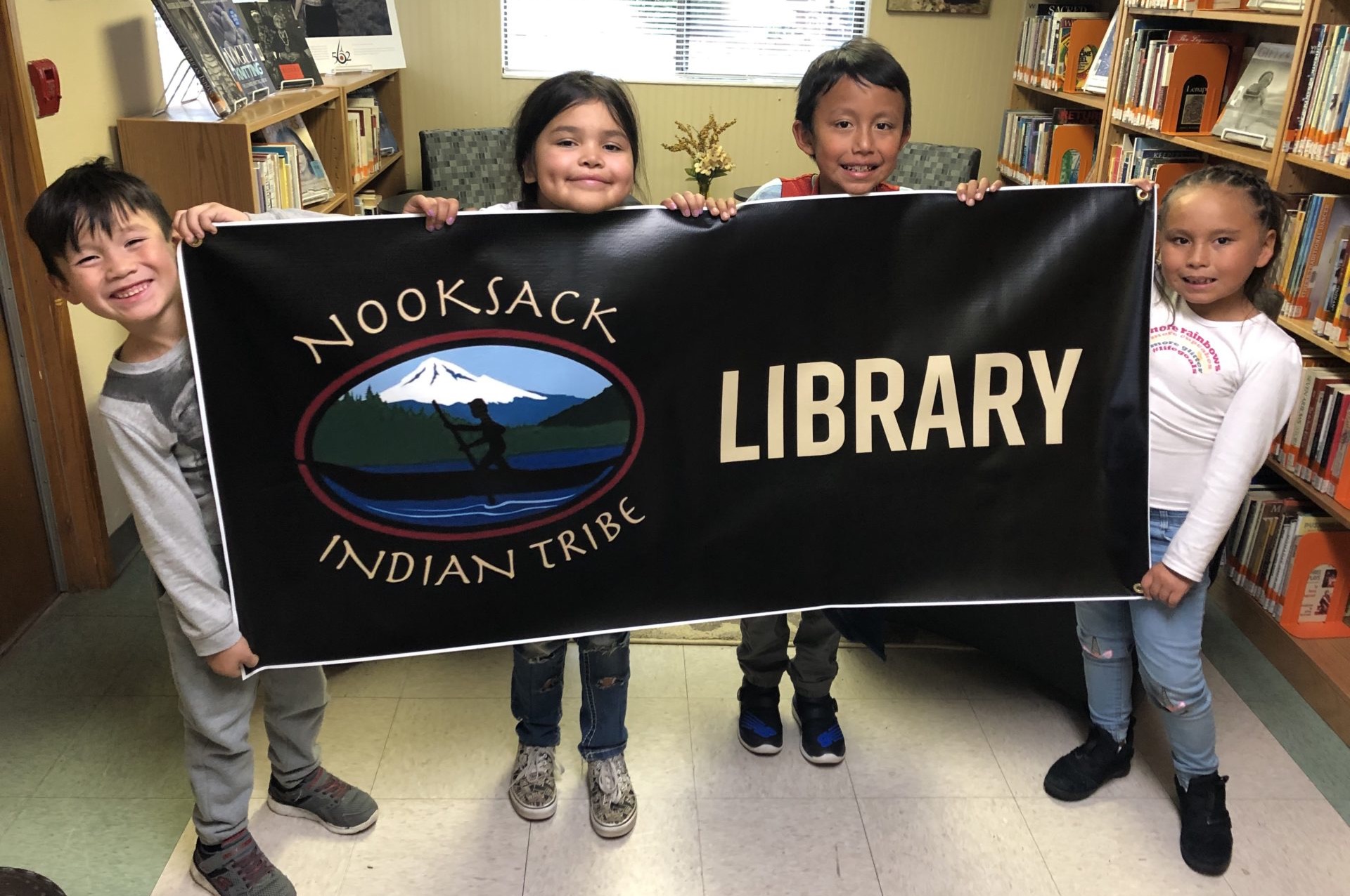 four children holding a banner that reads Nooksack Indian Tribe Library