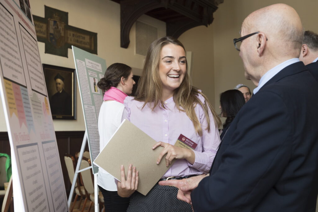 A photo of a smiling student talking to a BC professor during a poster session.