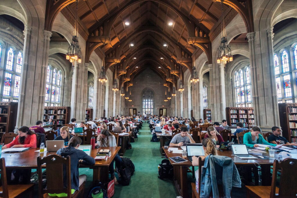 A photo of the interior of the Bapst Library filled with student studying around library tables.