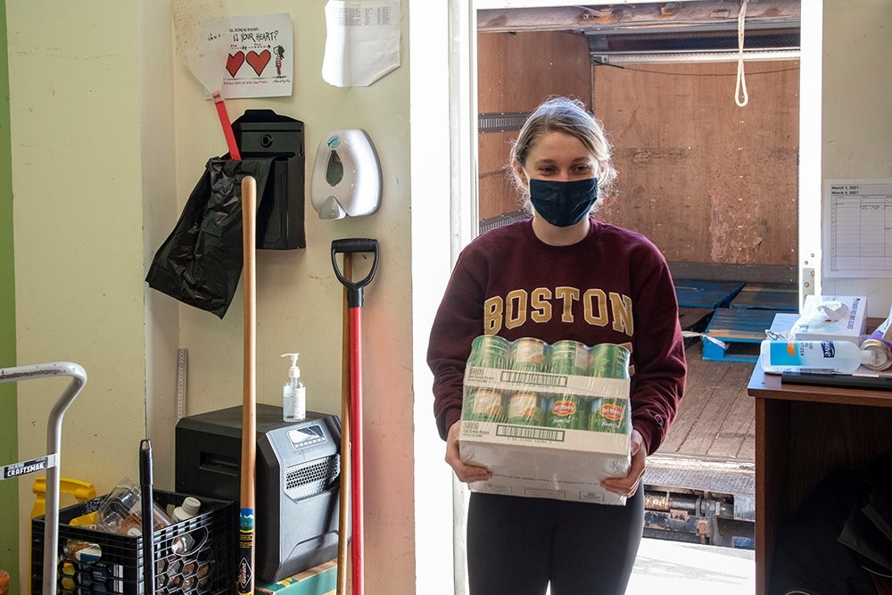 A student carrying a crate of canned goods