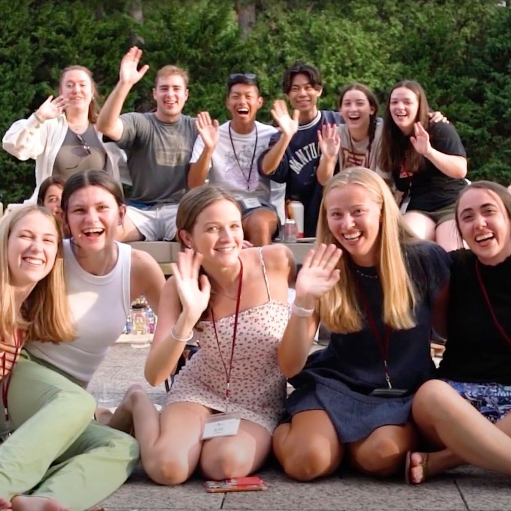 A group of Boston College undergrads smiling and waving together