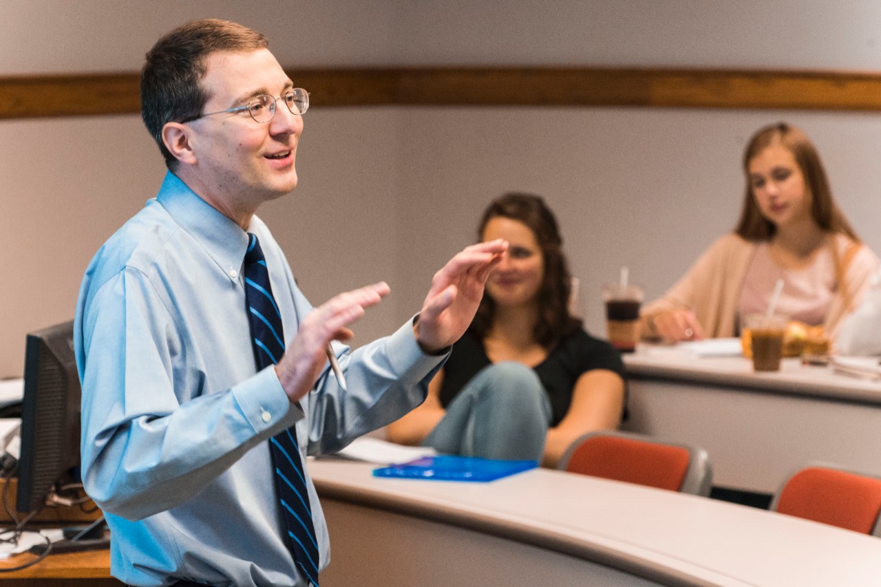 robert james teaching with two students smiling in the background