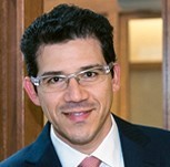 Man with clear-frame glasses in suit and tie