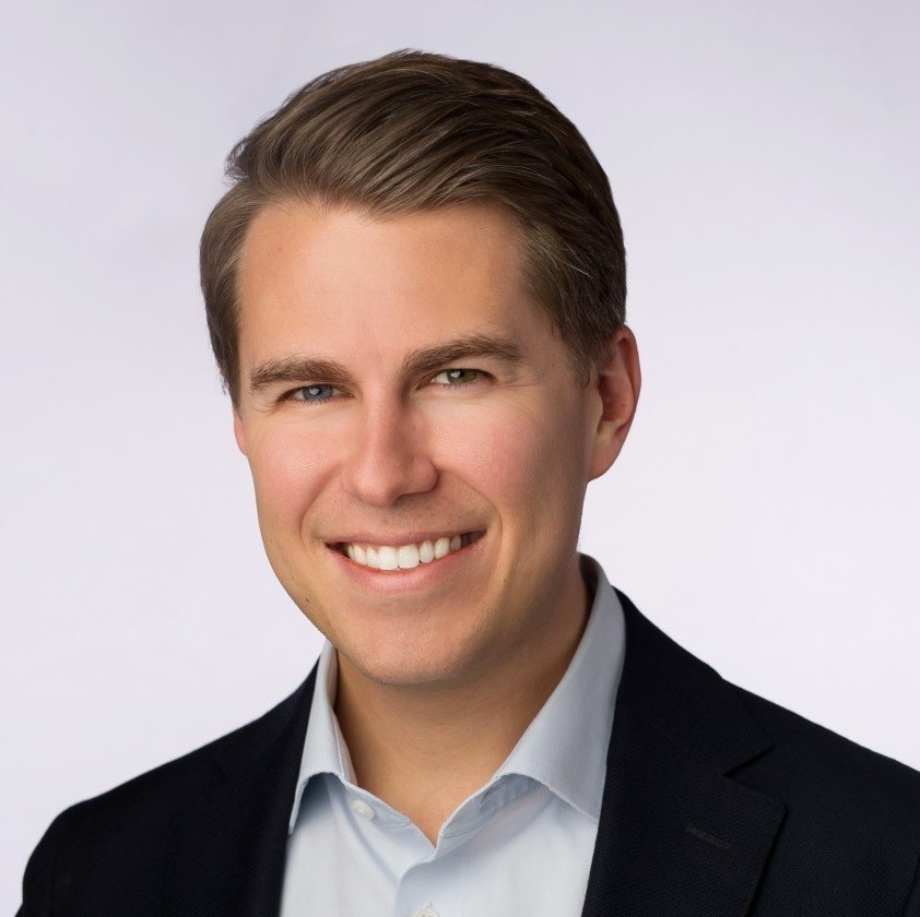 Miles Taylor, smiling younger white man in a button-up shirt and black plazer