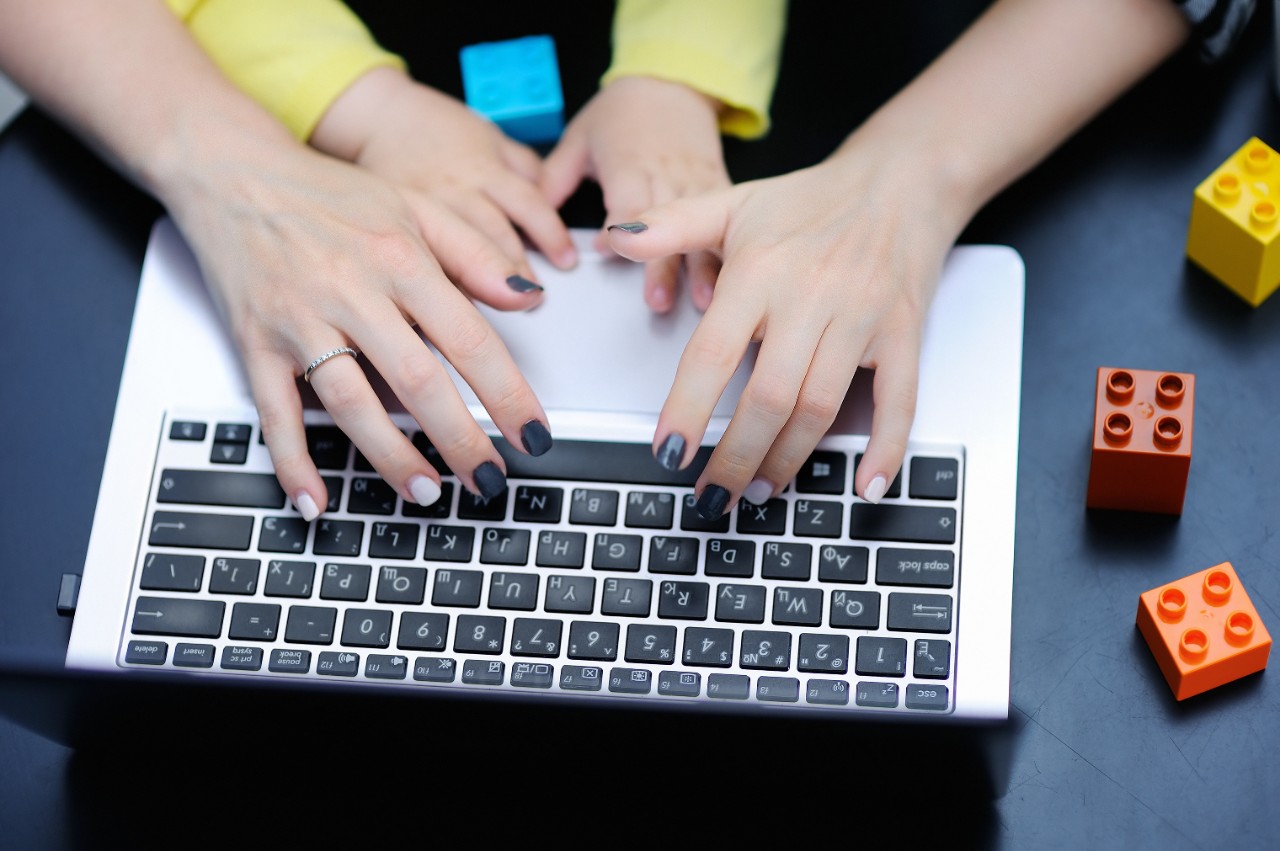 a mom and child working on a laptop