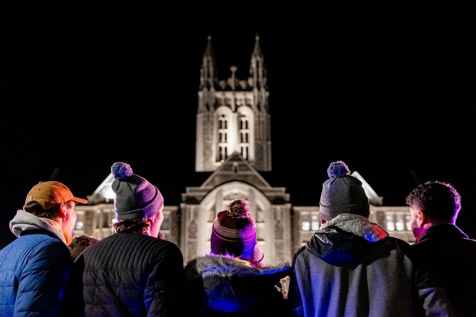 A group of people stand in front of Gasson at night.