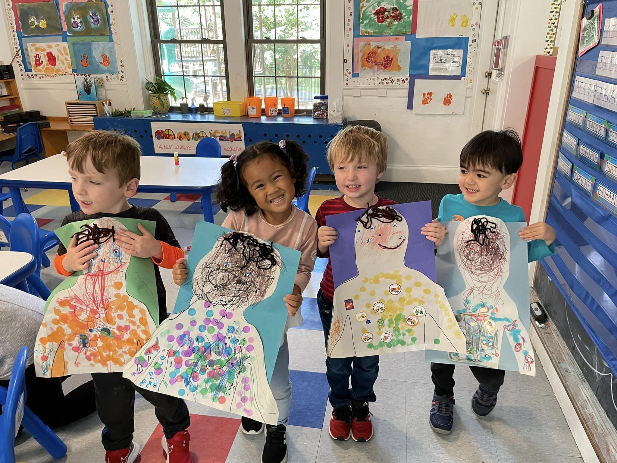 Children holding crafted self portraits