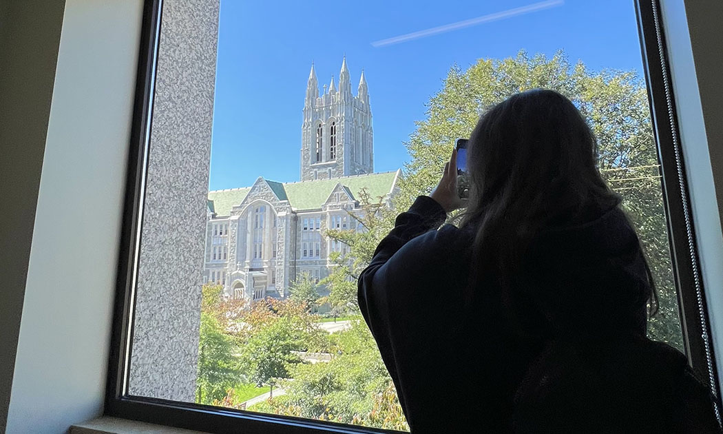 Student taking a photo of Gasson through a window
