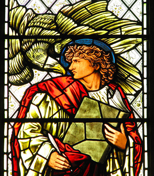 Stained glass window with a haloed man holding a book and an eagle over his shoulder