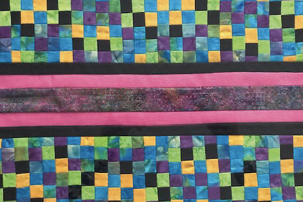 A quilt featuring a black, yellow, blue, and purple checkered pattern
