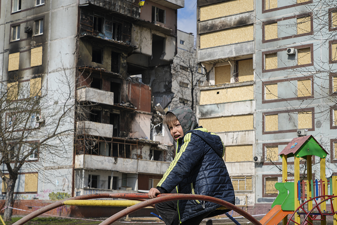 Zelenskyy's War A boy sits on a climbing frame in a playground in front of missile-damaged buildings ahead of a visit by Ukraine's President Volodymyr Zelenskyy in Zaporizhzhia, Ukraine, Monday, March 27, 2023. Zelenskyy has been increasing his travel across Ukraine as his country's war with Russia enters its second year. A team of journalists from The Associated Press traveled with Zelenskyy aboard his train for two nights as he visited troops along the front lines and communities that have been liberated from Russian control. (AP Photo/Efrem Lukatsky)