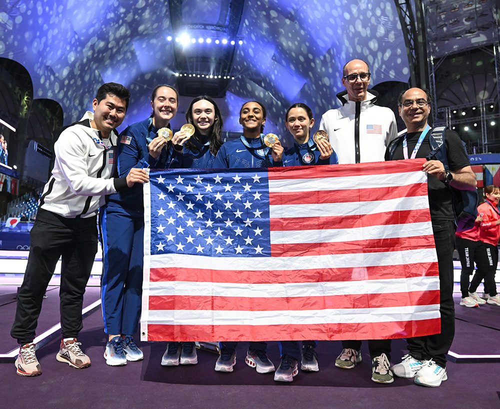 A group of people standing behind an American flag